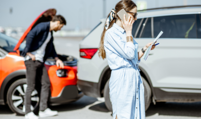 Woman calling for help after rear-end car accident, man inspecting damage; personal injury context.