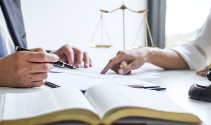 Lawyer and client reviewing legal documents with scales of justice in background; personal injury consultation.