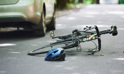 Damaged bicycle and helmet on road after accident with car, representing bicycle injury claim potential.
