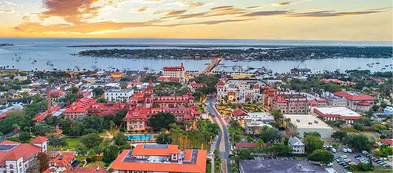 Aerial view of historic downtown St. Augustine, Florida at sunset with coastal waterfront and red rooftops.